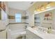 Bright bathroom features a shower-tub combo with white tile, decorative border, and a marble-top vanity at 14564 110Th Ter, Largo, FL 33774