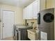 Well-lit laundry room featuring cabinetry, laundry sink, washer, dryer and water heater at 14564 110Th Ter, Largo, FL 33774