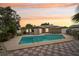 Backyard view of pool, patio, and outdoor furniture against a colorful sunset backdrop at 14564 110Th Ter, Largo, FL 33774