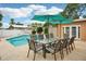 Outdoor pool and patio features a dining set with seating for eight and shade umbrella at 14564 110Th Ter, Largo, FL 33774