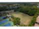 Scenic aerial showcasing tennis courts, a sprawling lawn, and verdant trees within a peaceful neighborhood setting at 14610 Mondavi Ct, Tampa, FL 33626