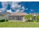 Home exterior showcasing a screened lanai and lush green lawn with tropical landscaping and palm trees at 14610 Mondavi Ct, Tampa, FL 33626