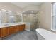 Bright bathroom featuring a soaking tub, glass-walled shower, natural light, and a wood vanity at 14610 Mondavi Ct, Tampa, FL 33626