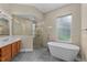 Bright bathroom featuring a soaking tub, glass-walled shower, natural light, and a wood vanity at 14610 Mondavi Ct, Tampa, FL 33626
