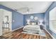 Blue bedroom featuring a queen bed, wood floors, and a window with natural light at 1521 Brittany Ct, New Port Richey, FL 34655