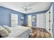 Blue bedroom with wood floors, ceiling fan, and view to closet and adjoining room at 1521 Brittany Ct, New Port Richey, FL 34655