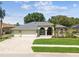 Charming single-story home with a three-car garage, manicured lawn, and inviting brick-paved driveway at 1521 Brittany Ct, New Port Richey, FL 34655
