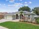 Charming single-story home with well-manicured lawn, arched entryway, and three-car garage at 1521 Brittany Ct, New Port Richey, FL 34655