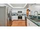 Well-lit kitchen features stainless steel appliances, white cabinets, and wood flooring at 1521 Brittany Ct, New Port Richey, FL 34655