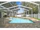 Screened in outdoor pool and lanai area with brick pavers and mature trees at 1521 Brittany Ct, New Port Richey, FL 34655
