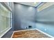 Inviting blue room featuring wood-look floors, a large window, and neutral trim at 1521 Brittany Ct, New Port Richey, FL 34655