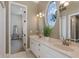 Elegant bathroom featuring a double sink vanity, an oval window with a serene view, and a mirrored wall at 1834 Daiquiri Ln, Lutz, FL 33549