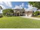 Stately home featuring a lush green lawn, attached three car garage, and manicured landscaping at 1834 Daiquiri Ln, Lutz, FL 33549