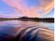 Calm lake surface reflects stunning pink and blue sunset sky, with tree-lined horizon at 1834 Daiquiri Ln, Lutz, FL 33549