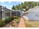 Spacious backyard with brick walkway, a screened in pool and adjacent garage at 212 W Powhatan Ave, Tampa, FL 33604