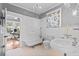 A view of a bathroom, featuring white subway tile, a clawfoot tub, and views to a bedroom and office area at 212 W Powhatan Ave, Tampa, FL 33604