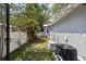 Side yard view featuring a white fence, mature trees, and the exterior of the well-maintained house at 212 W Powhatan Ave, Tampa, FL 33604