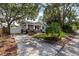Charming bungalow-style home with a welcoming front porch, lush landscaping, driveway and fenced area at 212 W Powhatan Ave, Tampa, FL 33604