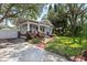 Charming bungalow-style home with a welcoming front porch, lush landscaping, driveway and fenced area at 212 W Powhatan Ave, Tampa, FL 33604