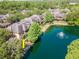 Aerial view of townhomes with tile roofs surrounding a pond with fountain and beautiful mature trees at 2173 Tuscany Trce # 8, Palm Harbor, FL 34683