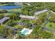 Aerial view of buildings surrounded by lush greenery with a community pool, parking area, and meticulously landscaped grounds at 2173 Tuscany Trce # 8, Palm Harbor, FL 34683