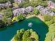 Birds-eye view of townhomes with tile roofs surrounding a pond with fountain and lush trees at 2173 Tuscany Trce # 8, Palm Harbor, FL 34683