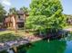 Exterior view of the house from the pond, showing lush landscaping and mature trees at 2173 Tuscany Trce # 8, Palm Harbor, FL 34683