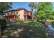 View of a lakeside two-story apartment with large trees, a screened patio, and sidewalk at 2173 Tuscany Trce # 8, Palm Harbor, FL 34683