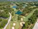 Aerial view of a lush green golf course surrounded by tall trees and tranquil ponds with sandy bunkers at 2173 Tuscany Trce # 8, Palm Harbor, FL 34683
