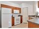Functional kitchen with white appliances, wood cabinets, and tiled flooring for easy upkeep at 2173 Tuscany Trce # 8, Palm Harbor, FL 34683