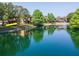 A lakeside view showcasing a lake, green trees, a fountain, and apartment complex at 2173 Tuscany Trce # 8, Palm Harbor, FL 34683