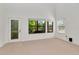 Bright living room featuring plush carpeting, door to outside, and large windows overlooking the green landscape at 2173 Tuscany Trce # 8, Palm Harbor, FL 34683