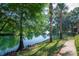 A tranquil pond with lush greenery, a fountain, and shaded trees and sidewalk at 2173 Tuscany Trce # 8, Palm Harbor, FL 34683