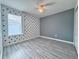 Inviting bedroom with a modern color scheme, ceiling fan, and grey wood-style laminate flooring at 2325 Via Bella Blvd, Land O Lakes, FL 34639
