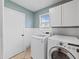 Bright laundry room featuring front load washer and dryer with white cabinets and blue-green walls at 2619 Green Valley St, Valrico, FL 33596