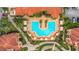 Overhead view of community pool and sun loungers with red-tiled roofs surrounding the property at 2705 Via Murano # 127, Clearwater, FL 33764