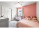bedroom featuring a pink accent wall, closet, bed, and a crib near the window at 30273 Marquette Ave, Wesley Chapel, FL 33545