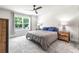 Bedroom with large window, gray carpet, and rustic wood nightstands and dresser at 30273 Marquette Ave, Wesley Chapel, FL 33545