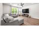 Living room featuring gray sectional sofa, large window with view, and mounted TV at 30273 Marquette Ave, Wesley Chapel, FL 33545