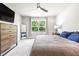 Main bedroom featuring large window, gray carpet, and rustic wood dresser with mounted tv at 30273 Marquette Ave, Wesley Chapel, FL 33545