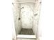 Updated shower with white marble tile and a dark tile floor, complete with a built-in niche at 3181 Deltona Blvd, Spring Hill, FL 34606
