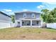 A spacious backyard features a covered patio, a gray-blue two-story house, solar panels, and a white fence at 3602 W Iowa Ave, Tampa, FL 33611