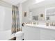 Bright bathroom with double vanity, tiled shower with curtain, and tiled floors at 3602 W Iowa Ave, Tampa, FL 33611