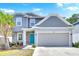 Charming two-story home with gray siding, stone accents, blue door, and a well-maintained front yard at 3602 W Iowa Ave, Tampa, FL 33611