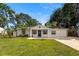 Charming single-story home featuring a well-manicured lawn, mature trees, and a welcoming front entrance with blue door at 4208 W Bay Vista Ave, Tampa, FL 33611