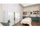 Bright spa room with a massage table, wood-look tile floor, floating shelves, and light-filtering curtains at 4286 Cairoli Ct, Wesley Chapel, FL 33543
