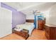 Cozy bedroom featuring hardwood floors, a ceiling fan, and a decorative purple accent wall at 4801 71St N St, St Petersburg, FL 33709
