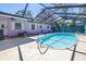 Enclosed pool area with a clear blue pool, surrounded by cement and a light purple house at 5010 109Th N Way, St Petersburg, FL 33708