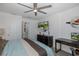 This stylish bedroom features a ceiling fan, mounted TV, dresser, a desk, and bright neutral walls at 5332 Riverwalk Preserve Dr, New Port Richey, FL 34653