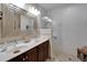 Bright bathroom showcasing double sinks, a large mirror, and a modern tiled shower with built-in shelving at 5646 Sunset Falls Dr, Apollo Beach, FL 33572